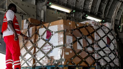 A Qatari Red Crescent member stands next to shipment of humanitarian aid bound for the Gaza Strip being unloaded off a military transport aircraft after landing at Arish International Airport in North Sinai province on November 9, 2023. AFP