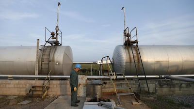 An employee at the Oelweg oil company, works near oil tanks at the site of an oil well in Oberlauterbach. Vincent Kessler / Reuters