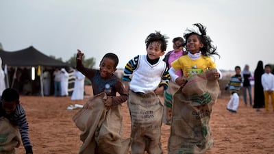 Jasim Eisa, 7, Badr Hamdan, 8, and Nadila Saleh, 7, sack jumping on Family Day, an event organized for the employees and the foster families of Dar Zayed for Family Care Silvia Razgova / The National
