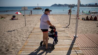 A woman, who is still recovering from long term effects of coronavirus, walks to the beach during a trip organised for vaccinated senior citizens in Benidorm, Spain. Getty Images