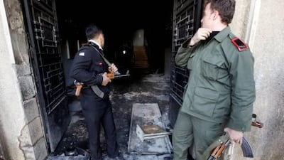 Policeman, left, and army soldier, right, look inside the court building set on fire by anti-government protesters in the southern city of Daraa, Syria.