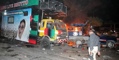 A Pakistani policeman stands beside of a burning police van in front of a vehicle carrying of former Pakistani prime minister Benazir Bhutto at the bomb explosion site in Karachi on October 18, 2007. AFP