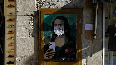 A poster by Italian urban artist Salvatore Benintende aka "TVBOY" depicting Leonardo da Vinci's Mona Lisa wearing a protective face mask in Barcelona. AFP
