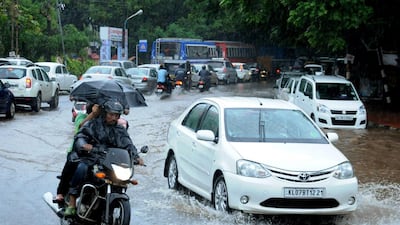 Indian commuters make their way along a waterlogged road during heavy monsoon rains in Kochi. AFP