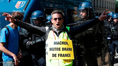 A gilets jaunes protester sporting a sign reading: "Macron, our French drama" in a play on words. Zakaria Abedlkafi / AFP