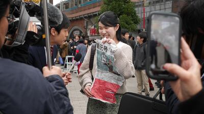 A woman holding a local paper reporting the announcement of the new era name "Reiwa" while giving a television interview in Tokyo. AFP