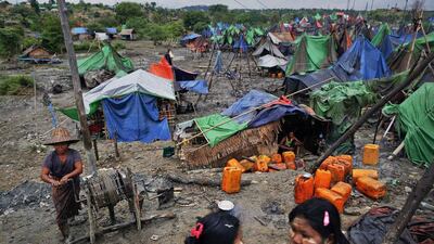 A woman manually extracts oil from a small well as girls chat at an oil field in the Minhla township of the Magwe in Myanmar. Damir Sagolj / Reuters