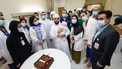 Baby Fatima is pictured with her father Suliman and the medical team following her life-saving surgery. Photo: ADSCC