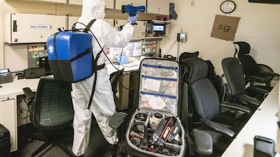 A cleaner at the White House sprays disinfectant after US President Donald Trump returned to the White House. EPA