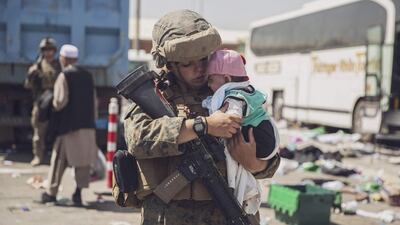 A US Marine carries a baby as the family is processed through the Evacuation Control Centre at the airport in Kabul. AFP