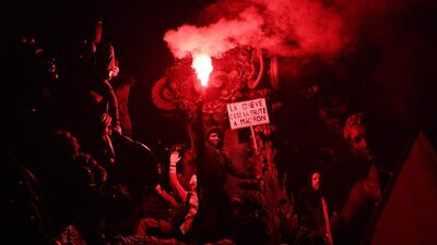 A protester holds a banner reading "The strike is Macron's fault" as he takes part in a demonstration in Paris, on Tuesday. AFP