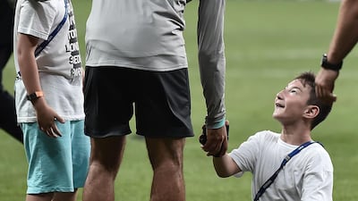 Liverpool's Egyptian midfielder Mohamed Salah plays football with a child at the end of a training session. AFP