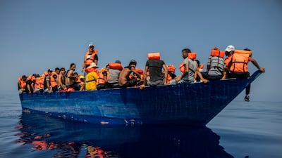 A group, thought to be migrants from Tunisia, aboard a flimsy wooden boat wait to be assisted by rescue teams near the Italian island of Lampedusa. AP