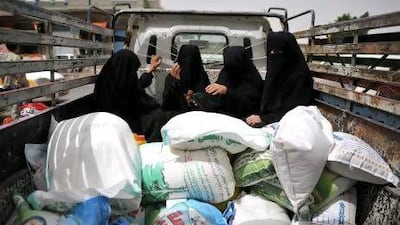 Yemeni women in Sanaa sit next to sacks of food aid provided by the UAE.