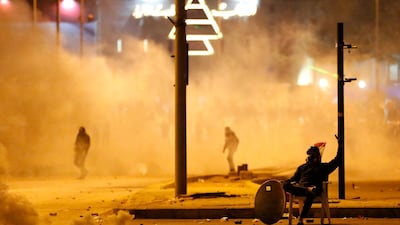 An anti-government protester covered by the smoke of the tear gas, sits in the middle of a street. AP Photo