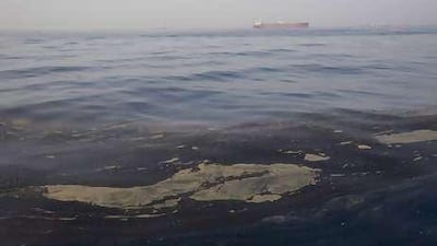 With a tanker of oil in the background, oil from a spill floats on the surface of the sea off the coast of Fujairah.