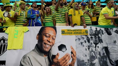 Fans next to a banner of football legend Pele during the World Cup match between Brazil and Cameroon at the Lusail Stadium in Doha, on December 2, 2022. AFP