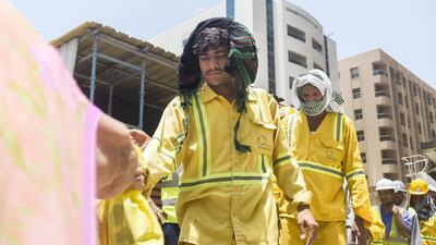Volunteers from the Ramadan Sharing Fridges initiative in Dubai distribute meals to construction workers in Bur Dubai. Reem Mohammed / The National