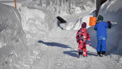 Children walk along a snow covered road in Gerold. EPA