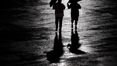 People walk across a rain-soaked car park after a baseball game between the Kansas City Royals and the New York Yankees in Kansas City, Missouri. AP Photo