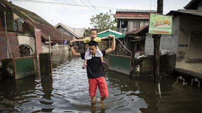A father carries his son on his shoulders as they cross a flooded street in the aftermath of Typhoon Mangkhut in San Simon, Pampanga on September 16. Noel Celis / AFP
