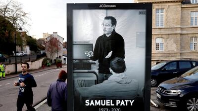 Pedestrians pass by a poster of French teacher Samuel Paty. AFP