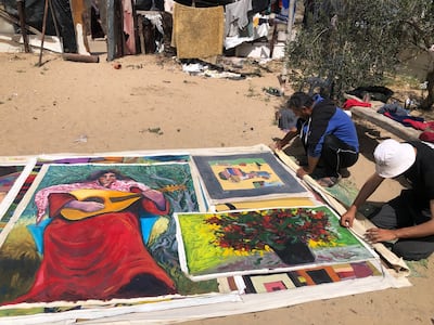 Mohammed Al-Hawajri and his younger son Mahmoud in Rafah, rolling the canvases they secured from their home and studio. Photo: Mohammed Al-Hawajri