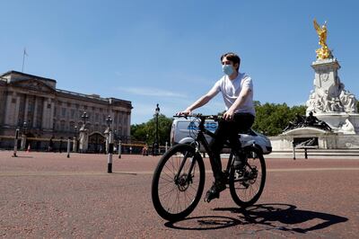 A man wearing a protective face mask cycles past Buckingham Palace. Reuters