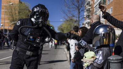 A Star Wars fan (L) disguised as a TIE fighter pilot greets a 'little Mandalorian' (R) during the Galaxy Day Parade in Madrid, Spain, 03 April 2022. The event is organized by Star Wars fan clubs in support of social associations focused on mental illness and functional diversity. EPA / Rodrigo Jimenez