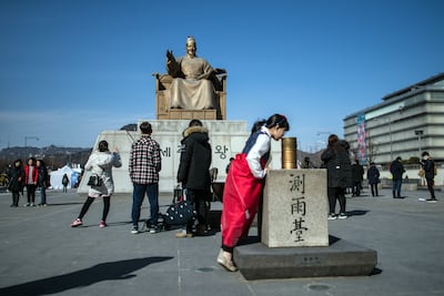 Tourists in front of King Sejong's statue at Gwanghwamun Square. Getty Images