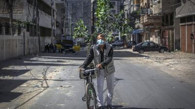 A Palestinian man wearing a protective mask due to the Covid-19 pandemic transports a tree sapling on his bicycle in Gaza city. AFP