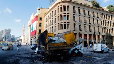 People walk past a burnt truck, set ablaze by protesters during clashes the night before in downtown Beirut following a demonstration against a political leadership they blame for the Beirut explosion. The bulk of Solidere's tenant's are in the downtown area which it rebuilt after the end of a 15-year civil war. AFP