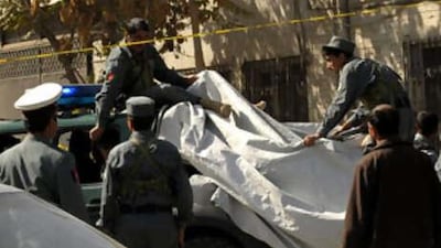 Afghan policemen sit on a vehicle carrying bodies at the site of a shoot-out in Kabul.