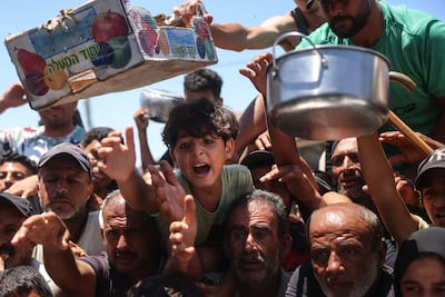 Displaced Palestinians reach out to receive hot meals from a charity kitchen in the Khan Younis refugee camp in southern Gaza. AFP
