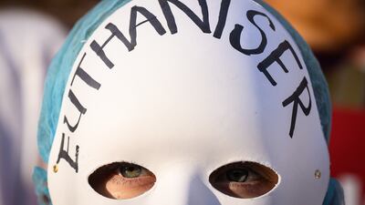 A supporter of the 'Not Dead Yet' campaign, which opposes the Assisted Dying Bill, wears a 'Euthaniser' mask outside the Houses of Parliament. Getty Images