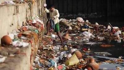An Indian man looks for recyclable items near a Hindu bathing site in New Delhi in the polluted Yamuna River. More than 2,400 litres of untreated sewage flow into the river every day.