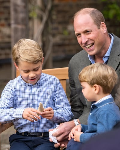 Prince George holds the tooth of a giant shark given to him by Sir David Attenborough in the gardens of Kensington Palace. AP