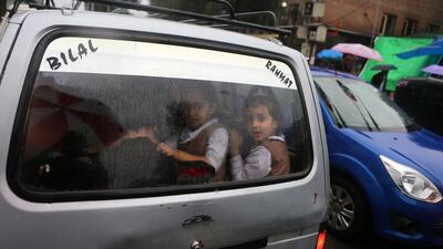 Kashmiri school children look through the rear wind window of a school cab as it travels in the rain along a road in Srinagar, India. Farooq Khan / EPA