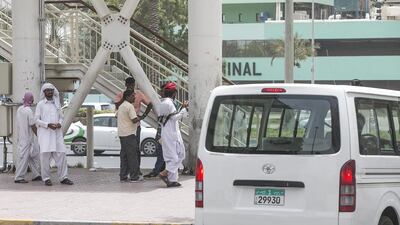 Illegal private cabs stand opposite the bus station and wait for passengers in Abu Dhabi. Mona Al Marzooqi / The National