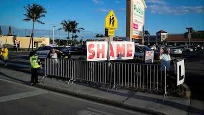 A protestor holds a sign as Donald Trump's motorcade heads to his Mar-a-Lago club, in West Palm Beach, Florida, April 18, 2019. Reuters