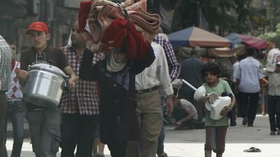 People carry their belongings as they flee the violence in Aleppo's Bustan Al Qasr neighborhood on Wednesday. Hosam Katan / AP