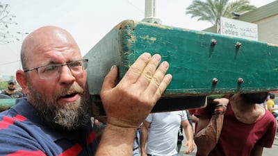A relative carries the coffin of a woman who died when an inflatable boat sank off the Lebanese port of Tripoli, at her funeral in the city. Reuters