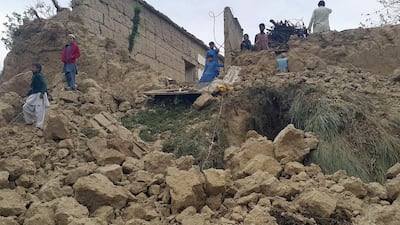 Pakistani residents gather next to the rubble of damaged houses following an earthquake in Bajaur. Anwarullah Khan / AFP Photo