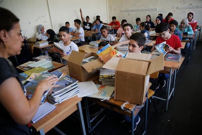 Palestinian refugee students receive new studying books inside their classroom in Beirut. AP