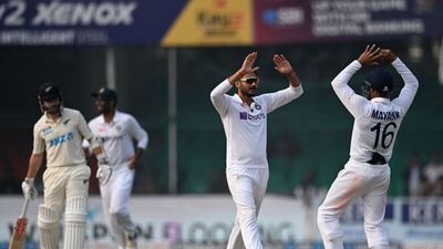 India's Axar Patel, centre, celebrates with teammate Mayank Agarwal after taking the wicket of New Zealand batsman Henry Nicholls. AFP