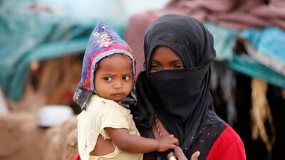 A girl carries a child near a hut in an improvised camp for internally displaced people in Hajjah. Reuters