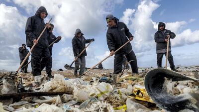 Workers clean the beach of the coastal town of Zouk Mosbeh, north of Beirut, on January 23, 2018. AFP