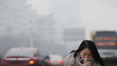 A woman uses a scarf to cover her face from the smog. Andy Wong / AP Photo