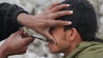 An Afghan street barber trims a customer's moustache in Kabul. AP