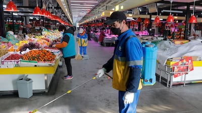 A worker wearing a protective mask sprays disinfectant at a market in Beijing, China. EPA